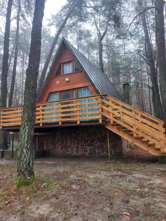 een hut in het bos met een houten terras bij Żuraw in Bocheniec