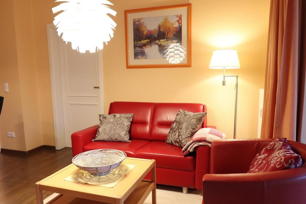 een woonkamer met een rode bank en een tafel bij Dünenschloss - 02-29 in Kühlungsborn
