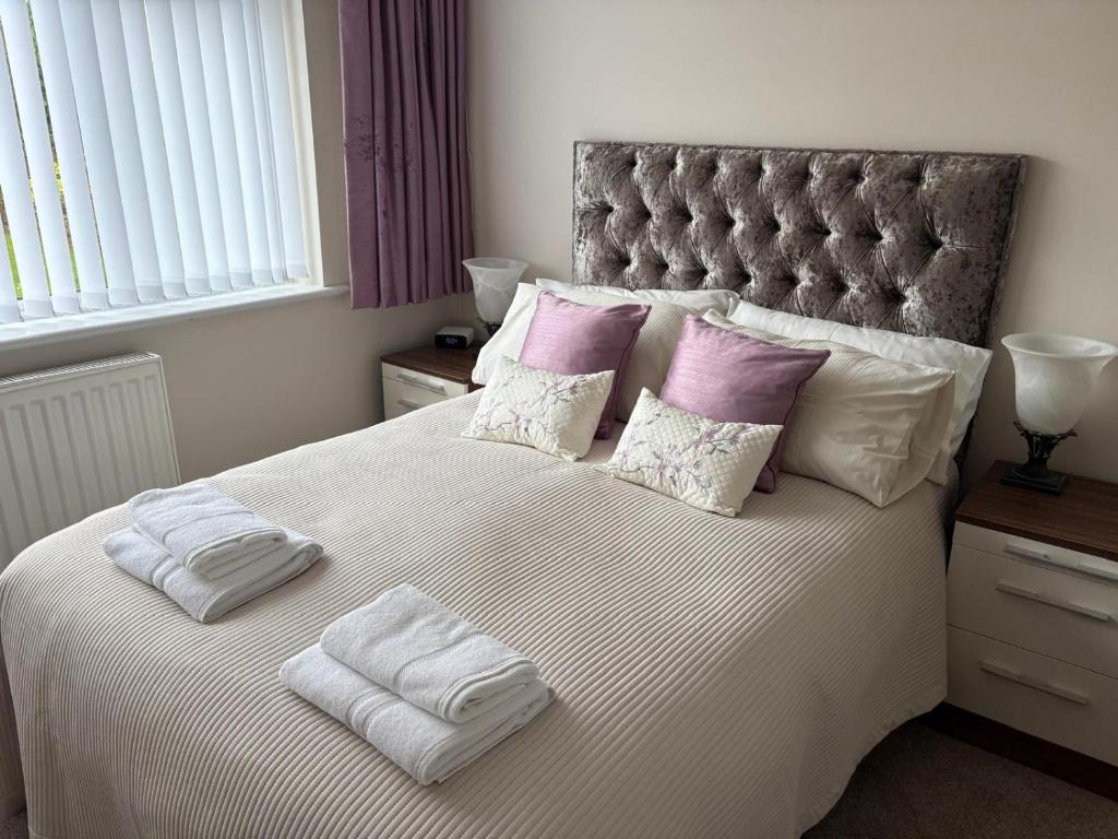 a bedroom with a large bed with two towels on it at The Knutsford Bungalow in Knutsford