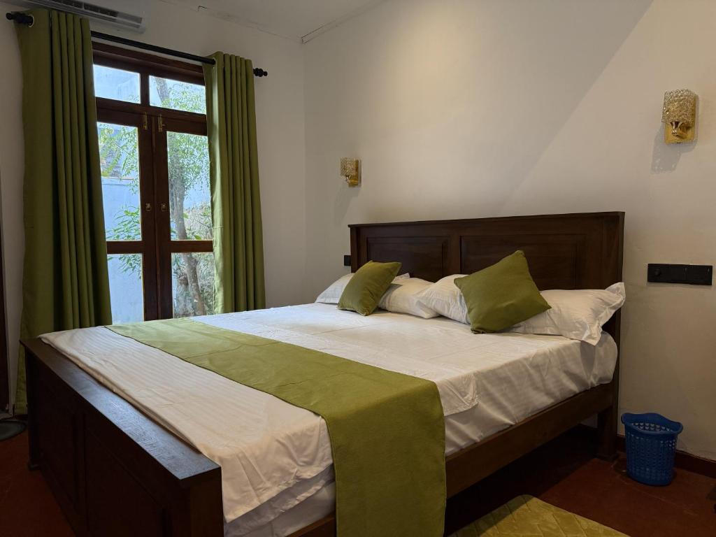 a bedroom with a bed with green pillows and a window at Villa By Dissa in Dikwella North