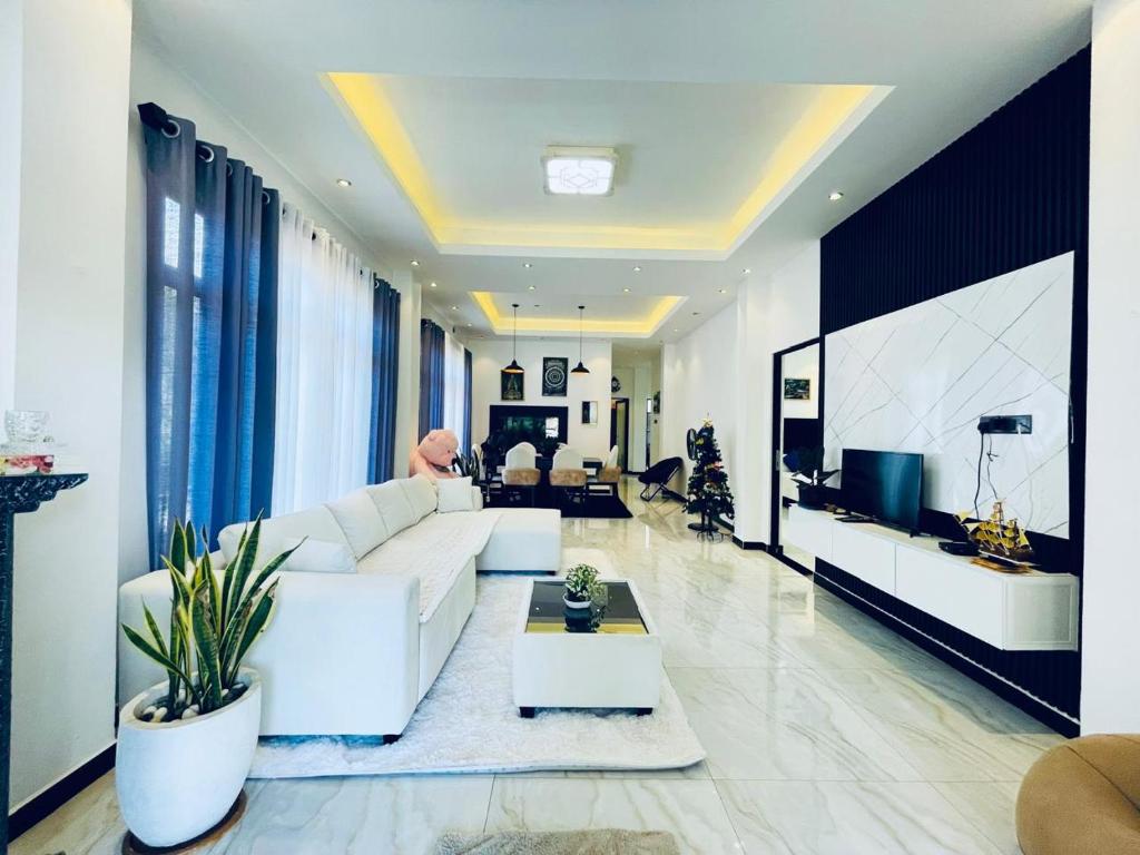 a living room with a white couch and a tv at Gimhani Villa Hiriketiya in Dickwella