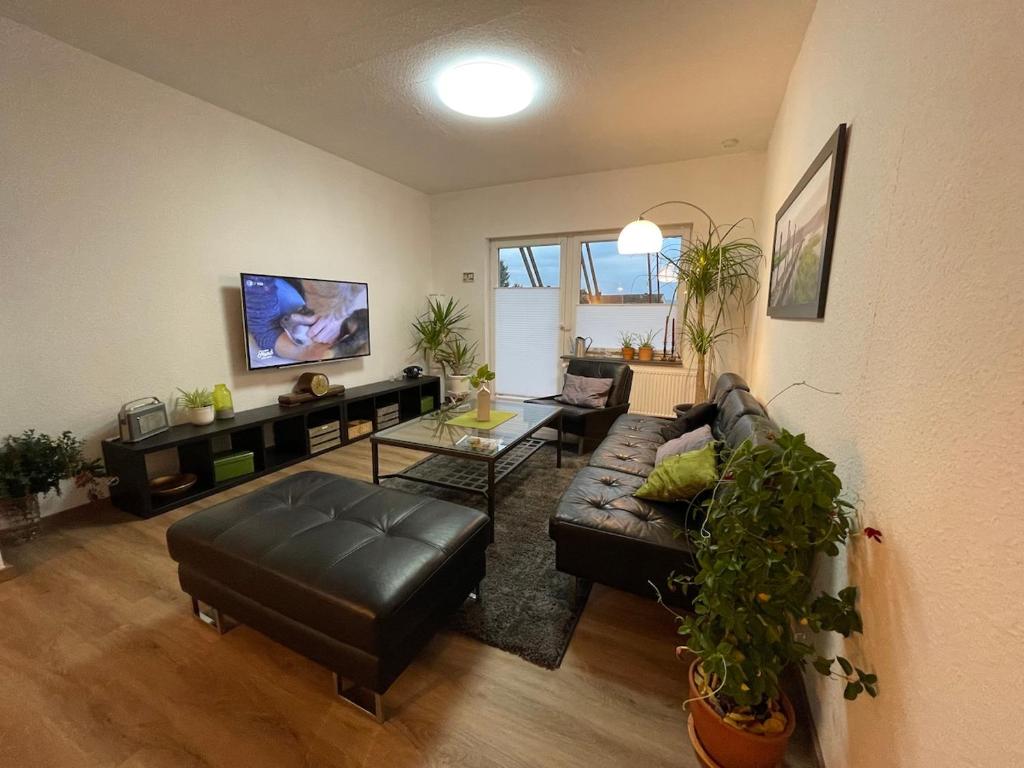 a living room with a black leather couch and a table at Close to Goettingen - unweit von Göttingen in Nörten-Hardenberg