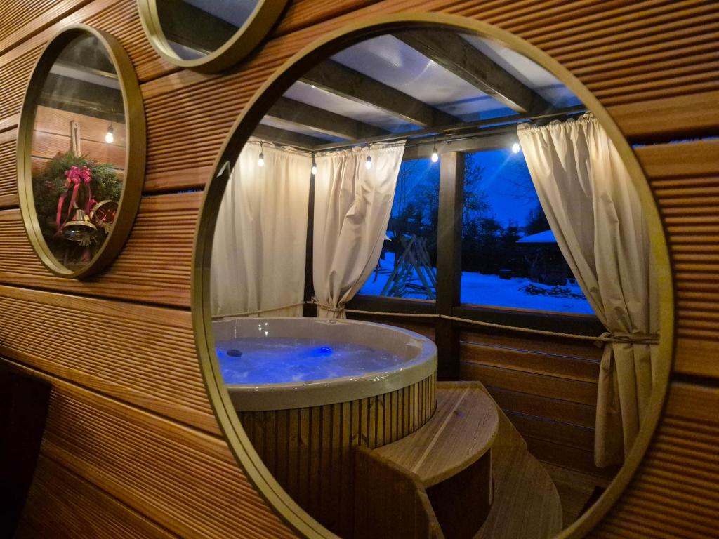 La salle de bains est pourvue d'une baignoire avec un miroir rond. dans l'établissement Apartament U Moniki, à Szaflary