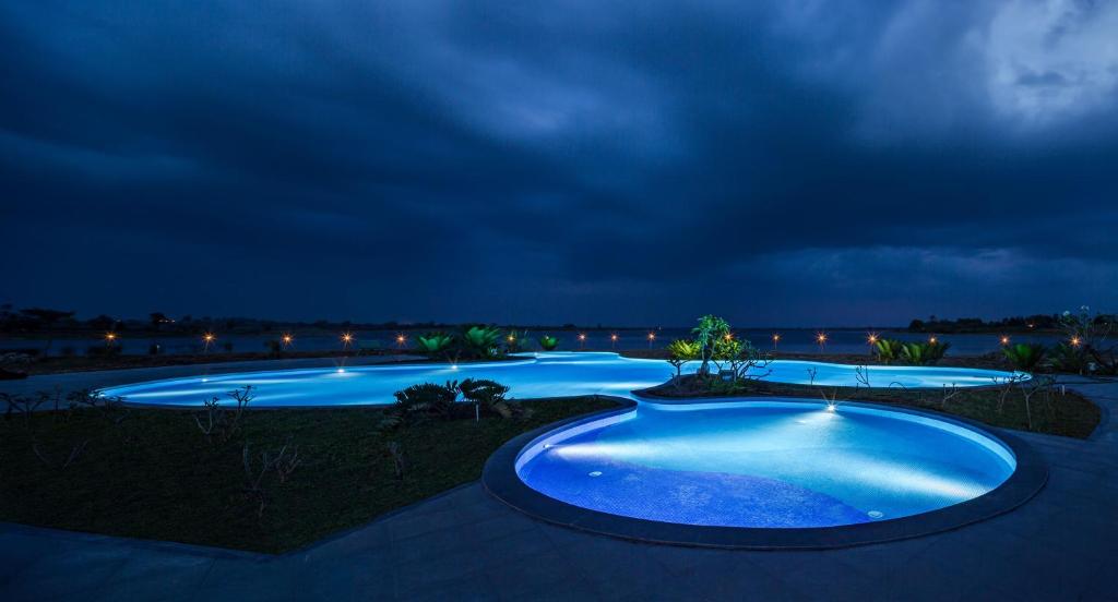 a group of three swimming pools at night at Discovery Village Kabini in Antarasante