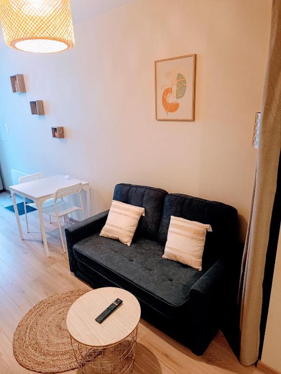 a living room with a black couch and a table at Le studio des quais in Bergerac