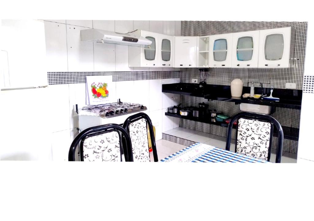 una cucina con mobili bianchi e un tavolo con sedie di Apê da Lili a Ilha de Boipeba