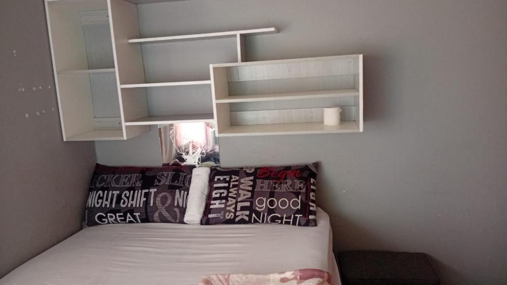 een kleine slaapkamer met een bed en witte planken bij Tk guesthouse in Sasolburg