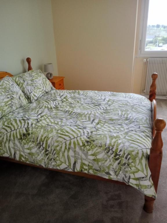 a bedroom with a bed with a green and white comforter at La Petite Maison Celtique in Saint-Nicolas-du-Pélem