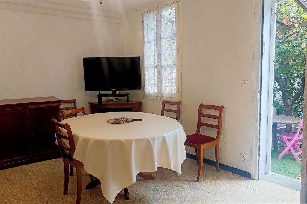 a room with a table and chairs and a television at Spacious house in Perpignan quiet and friendly in Perpignan