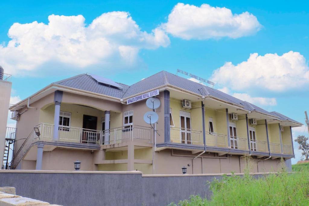 un grande edificio giallo con balcone in cima di Mpaata Empire Royal Suites a Hoima