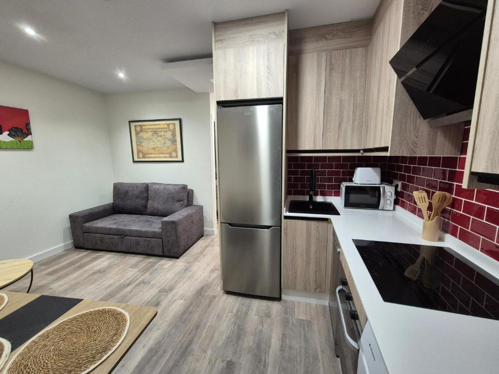 a kitchen with a stainless steel refrigerator and a chair at Escola in Ourense