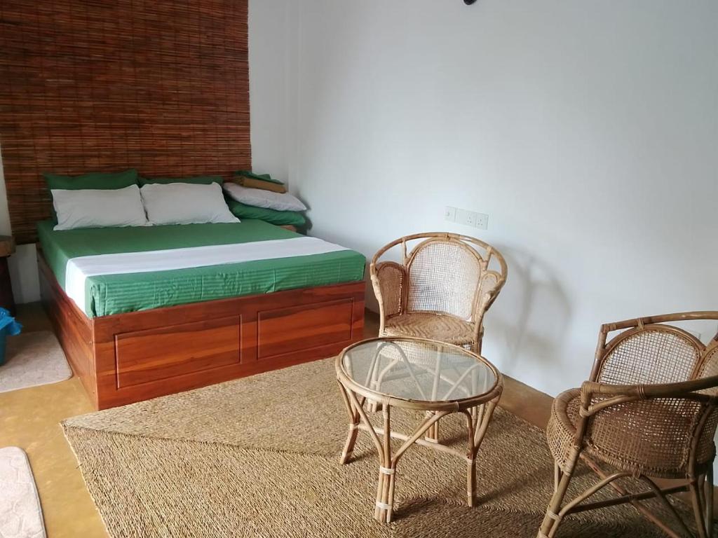 een slaapkamer met een bed, twee stoelen en een tafel bij sisi place in Dikwella