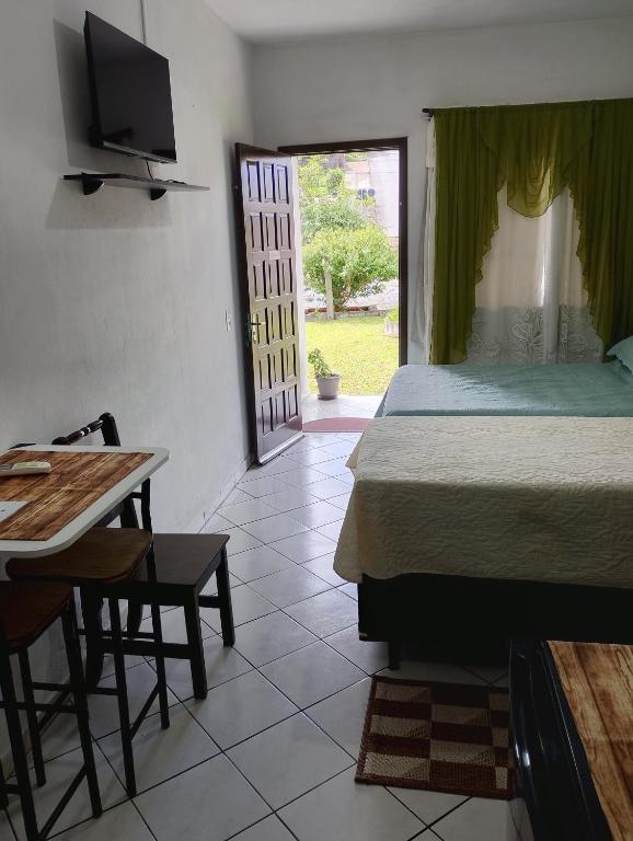 a bedroom with a bed and a table and a television at Suite do lar in Timbó