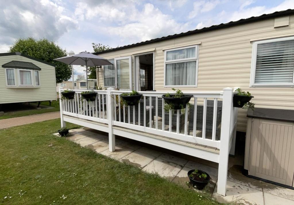 a white deck with an umbrella and potted plants at Seaside Sanctuary in Hemsby