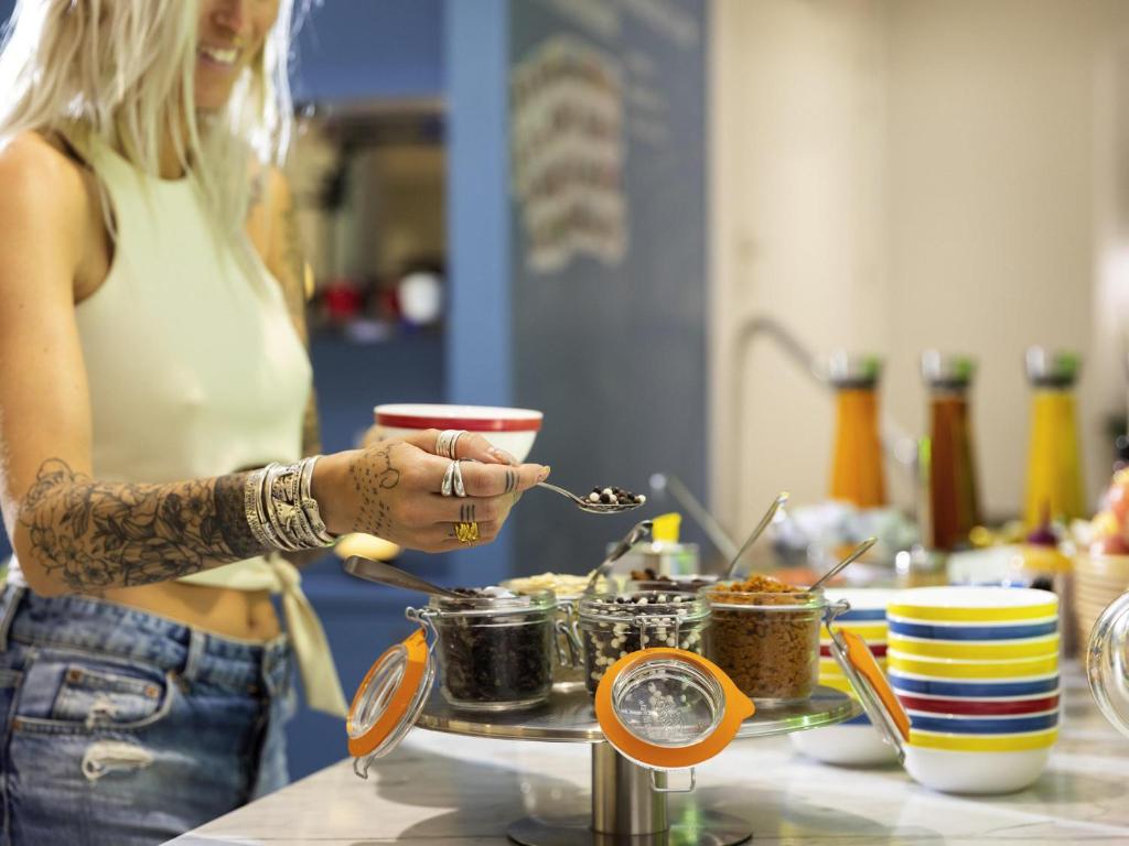 a woman is preparing food on a table at Ibis Styles Menton Centre in Menton