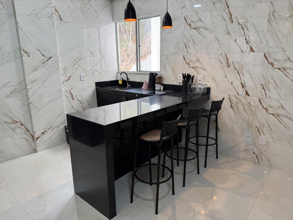 una cucina con bancone nero e sgabelli di Apartamento Central Próximo da praça Tiradentes e Hospital a Teófilo Otoni