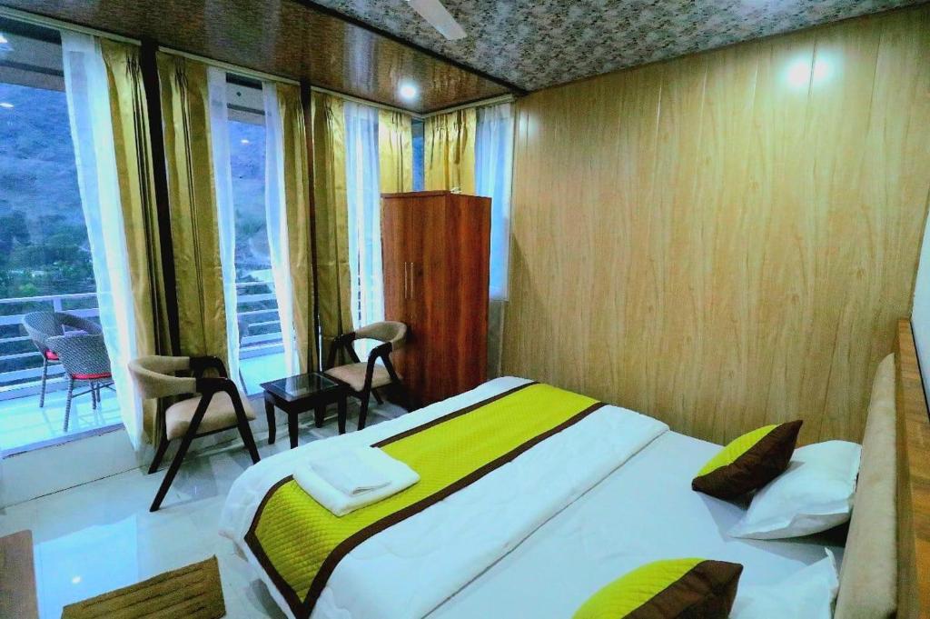 a bedroom with a bed and a large window at The Himalayan Majesty Hotel in Chopta