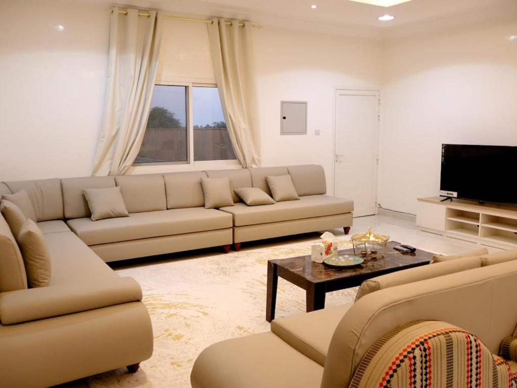 a living room with two couches and a tv at Alharamil Retreat in Ras al Khaimah