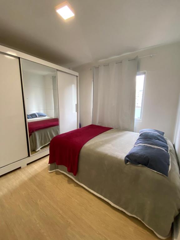 a bedroom with a large bed and a mirror at Apartamento Loft in Balneário Camboriú