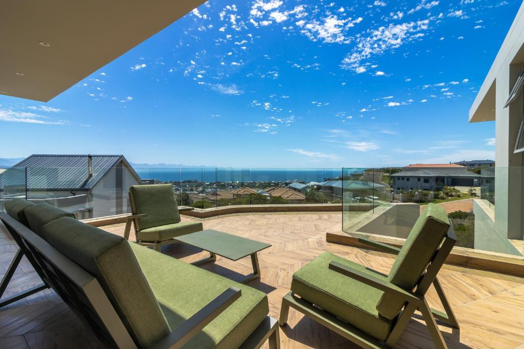 a balcony with chairs and a large glass window at Pinnacle Villa in Plettenberg Bay