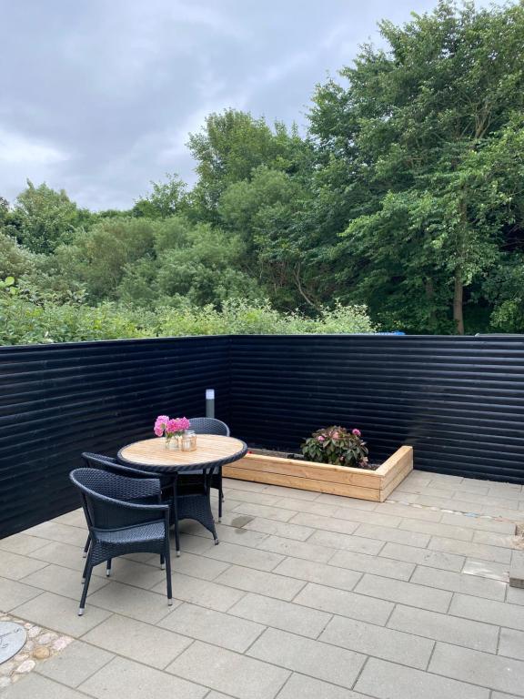 un patio con tavolo, sedie e una recinzione di Glentevej idyl ad Assens