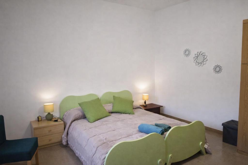 ein Schlafzimmer mit einem großen Bett mit grünen Kissen in der Unterkunft Casa Cera Arras in Dolianova