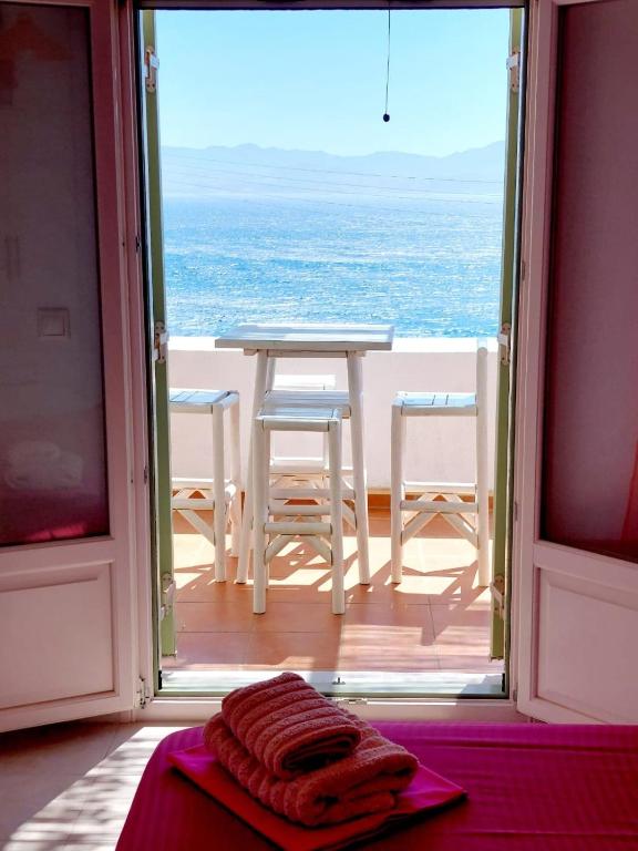 a table and chairs in a room with a view of the ocean at Parostalkinghouse in Piso Livadi