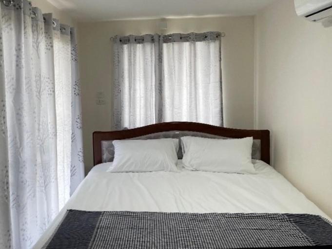 een bed met witte lakens en kussens in een slaapkamer bij Mae on country home in Ban On Luai