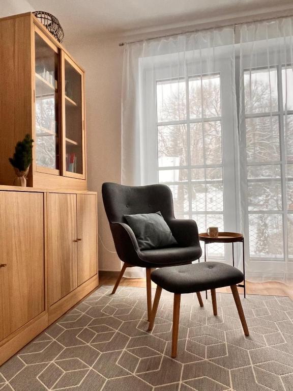 a chair and stool in a living room with a window at Apartmán Mařinka in Říčky