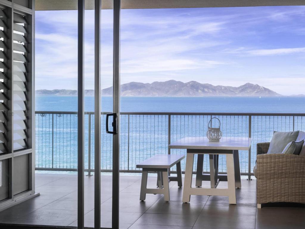 un balcon avec une table et une vue sur l'océan dans l'établissement Grand Mercure Apartments Magnetic Island, à Nelly Bay