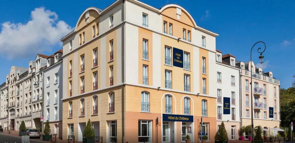 een groot geel en wit gebouw op een straat bij Hôtel Quality Suites Maisons-Laffitte Paris Ouest in Maisons-Laffitte
