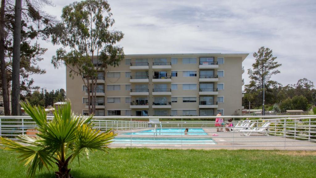 een gebouw met een zwembad voor een gebouw bij Departamento Sol in El Tabo