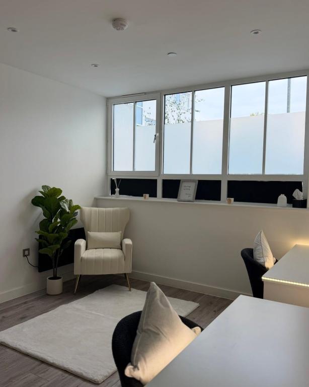 a living room with a couch and a chair and windows at Cosy flat that feels just like home in Leavesden Green