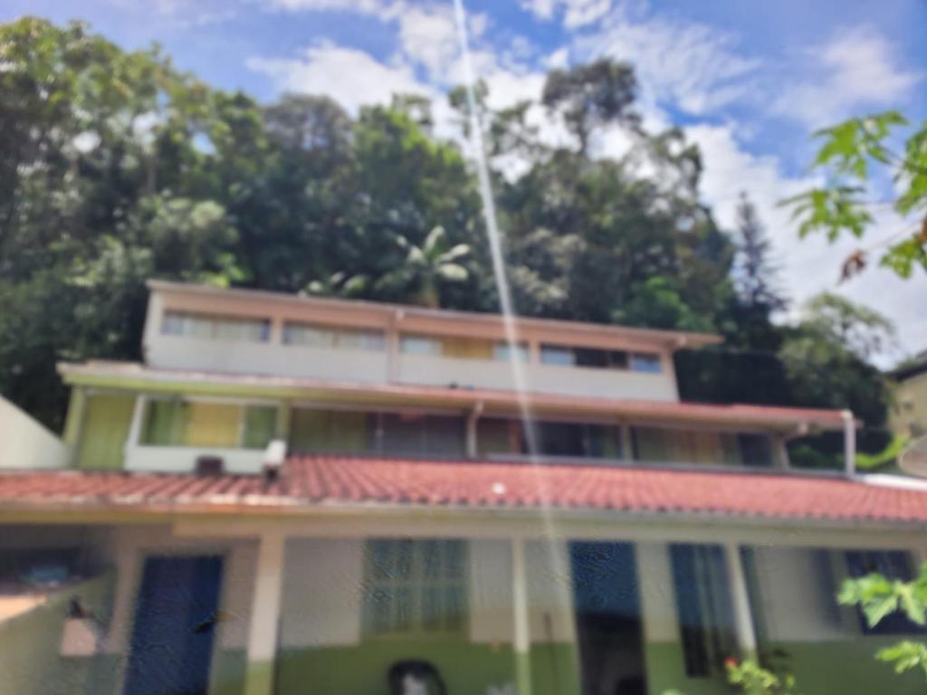 a green and white house with trees in the background at Quarto privado Brusque in Brusque