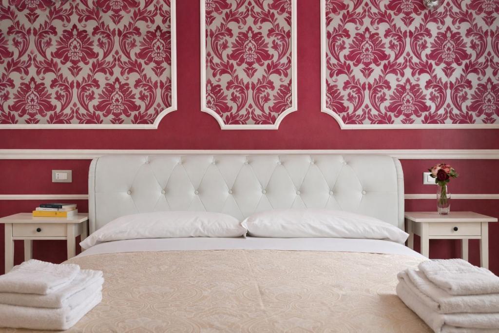 een slaapkamer met een wit bed met rode muren bij Opera Relais in Messina