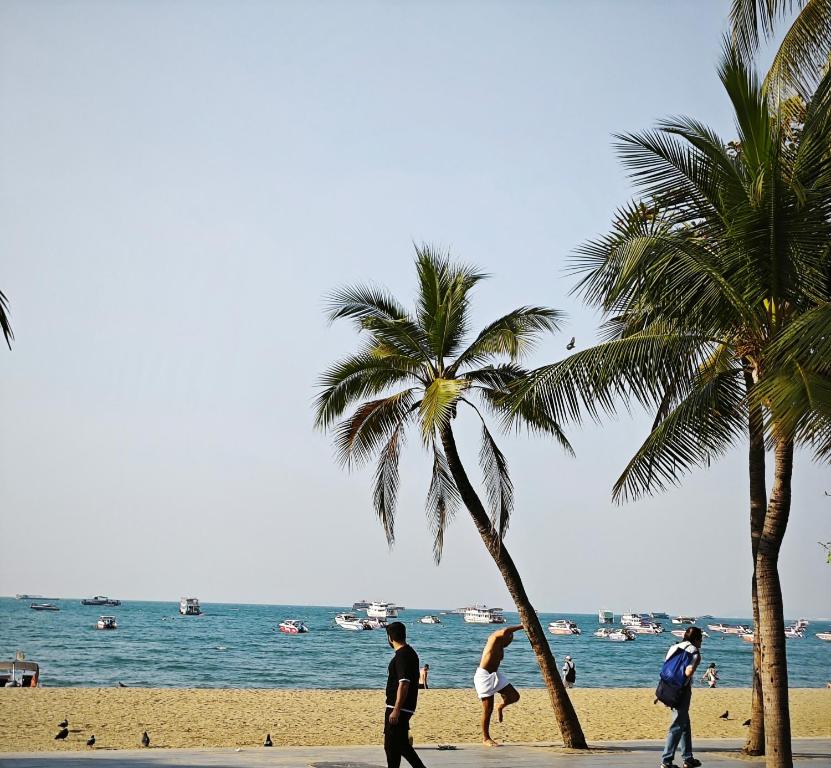 un gruppo di persone che camminano su una spiaggia con palme di TM Room For Rent a Centro di Pattaya