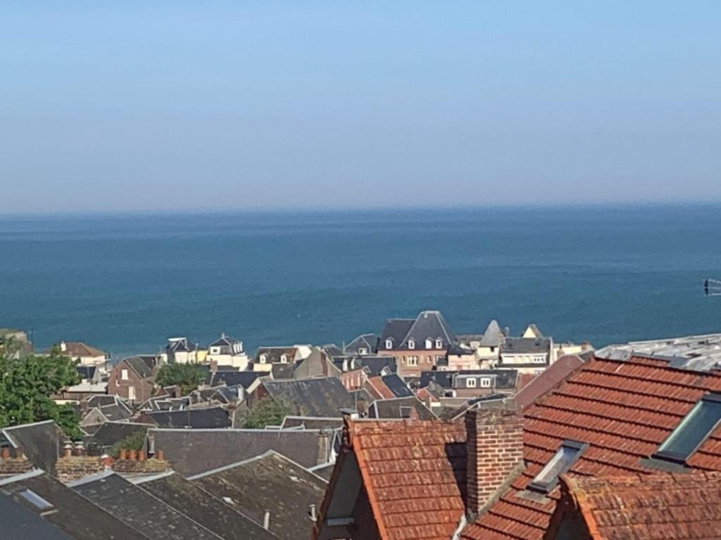 a city with roofs and the ocean in the background at Val et Mer House in Ault