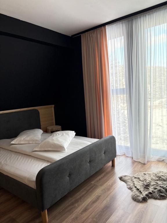 una camera da letto con un letto e una grande finestra di Black Chalet 2 a Vârtop