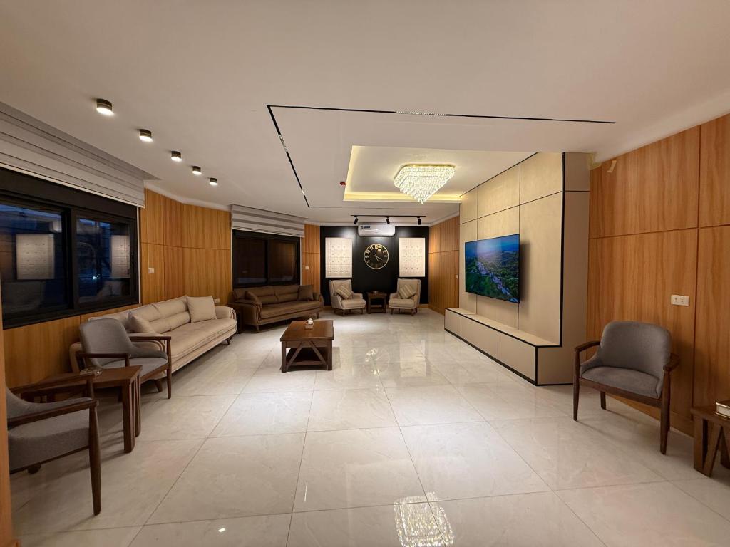 ein großes Wohnzimmer mit einem Sofa und einem TV in der Unterkunft Riva suites in Irbid