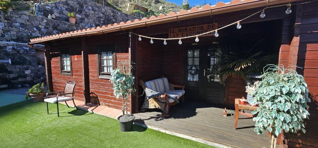 a wooden cabin with a porch and a chair on a lawn at CABAÑA Mirador de las Lagunetas in Vega de San Mateo