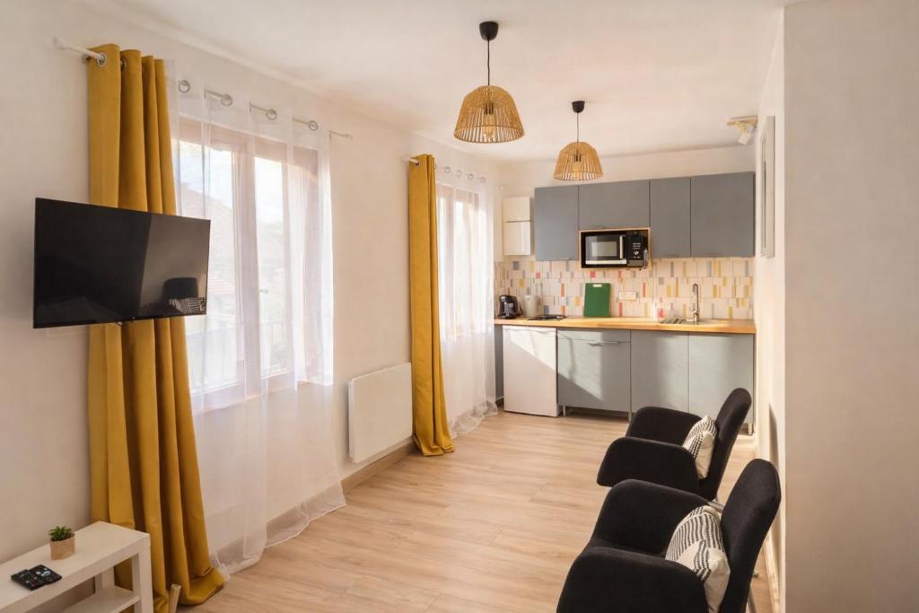 a living room with chairs and a kitchen with yellow curtains at Studio - Lit double - Proche Centrex & Disneyland in Noisy-le-Grand