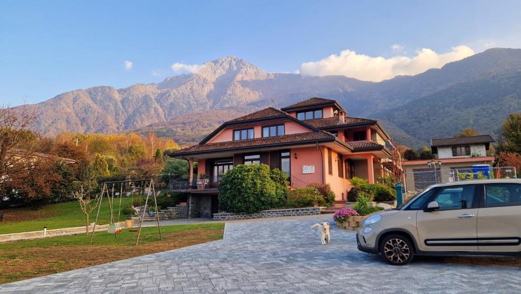 un'auto parcheggiata di fronte a una casa con le montagne di Foresteria Villa Simona a Colico