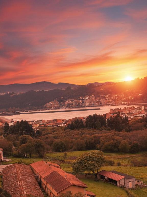 a sunset over a town with a river and a city at Complejo Rural Las Mimosas del Nalon in San Juan de la Arena