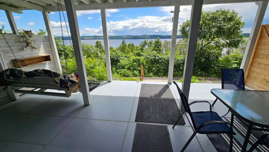 a person laying on a swing on a porch with a view of the water at Suite 3 Flèche du fjord vue Saguenay Mont Valin in Saint-Fulgence