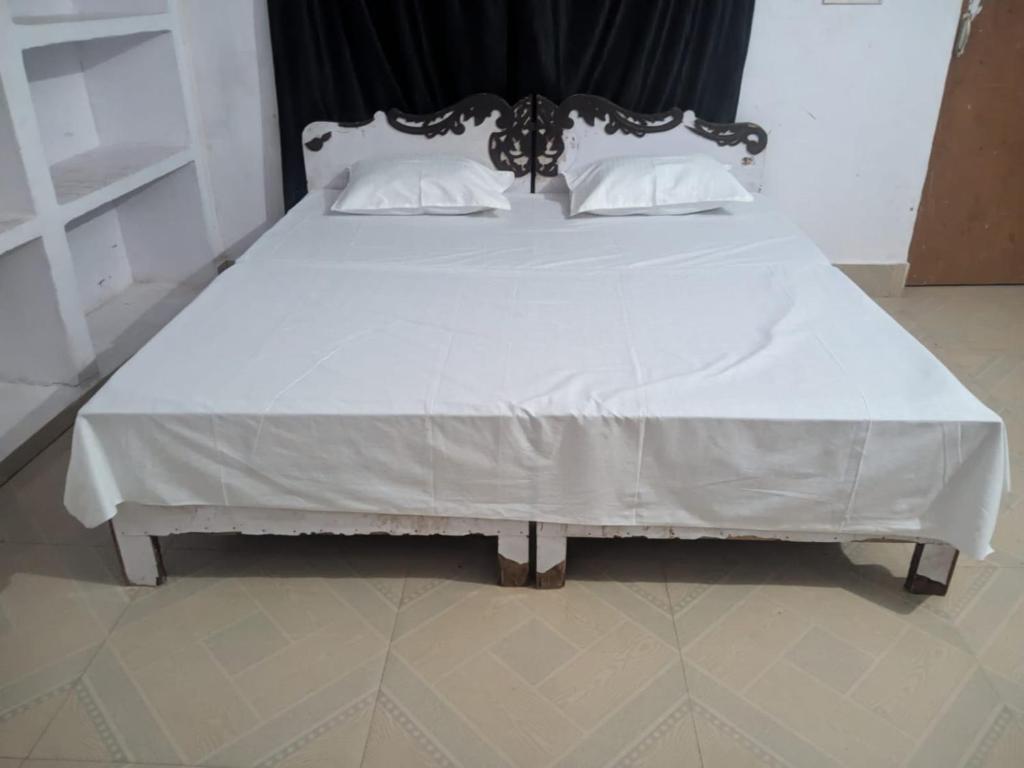a large bed with white sheets and pillows at Sangam Sathi in Prayagraj