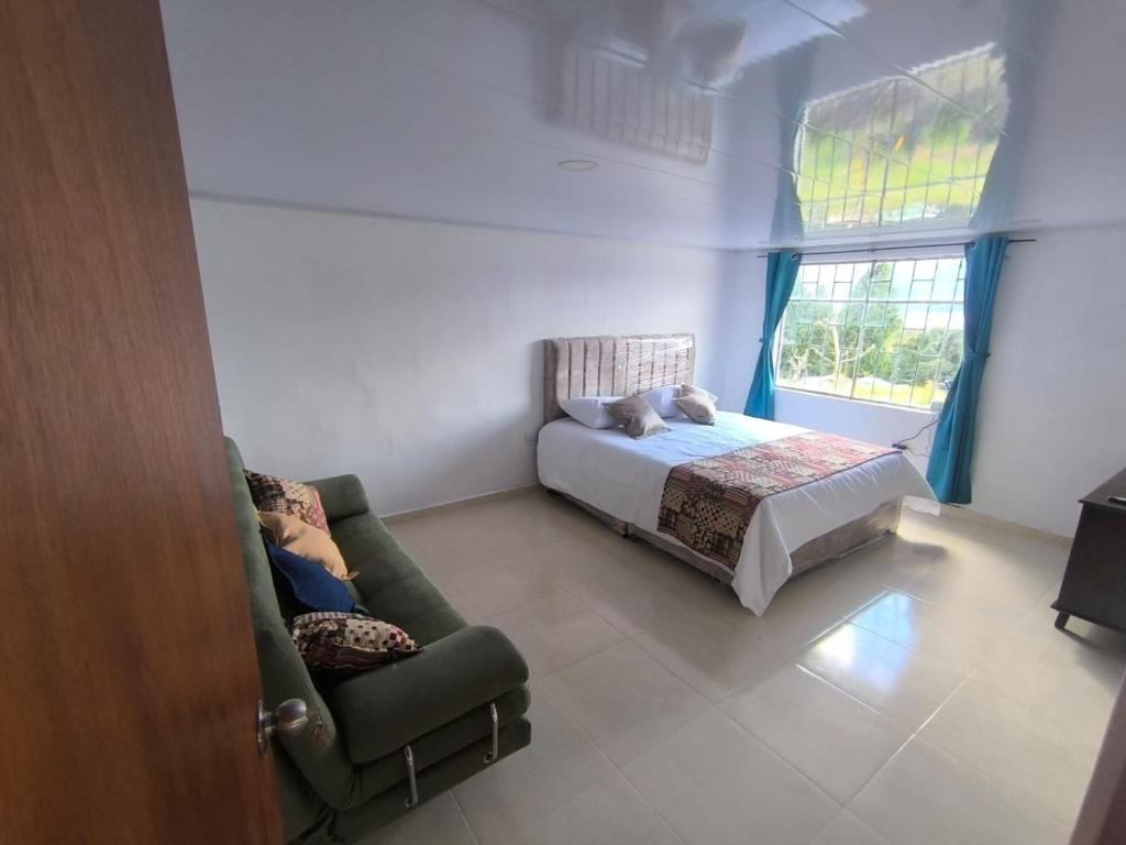a bedroom with a bed and a couch and a window at Cabaña El Laurel in Pasto