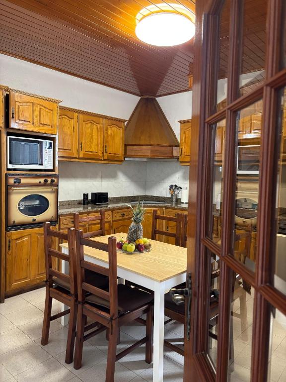 a kitchen with wooden cabinets and a table with fruit on it at Casa estrelicia II in Relógio do Poiso