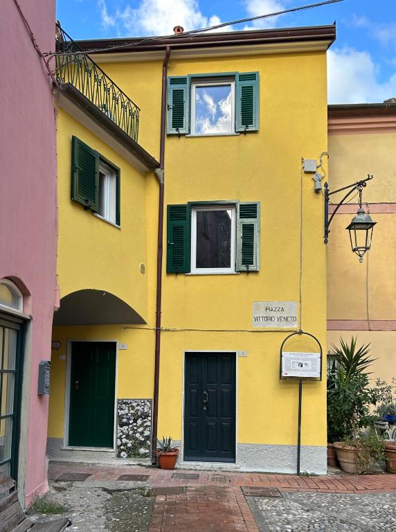 a yellow building with green windows and a street at Casa Camilla in Montemarcello
