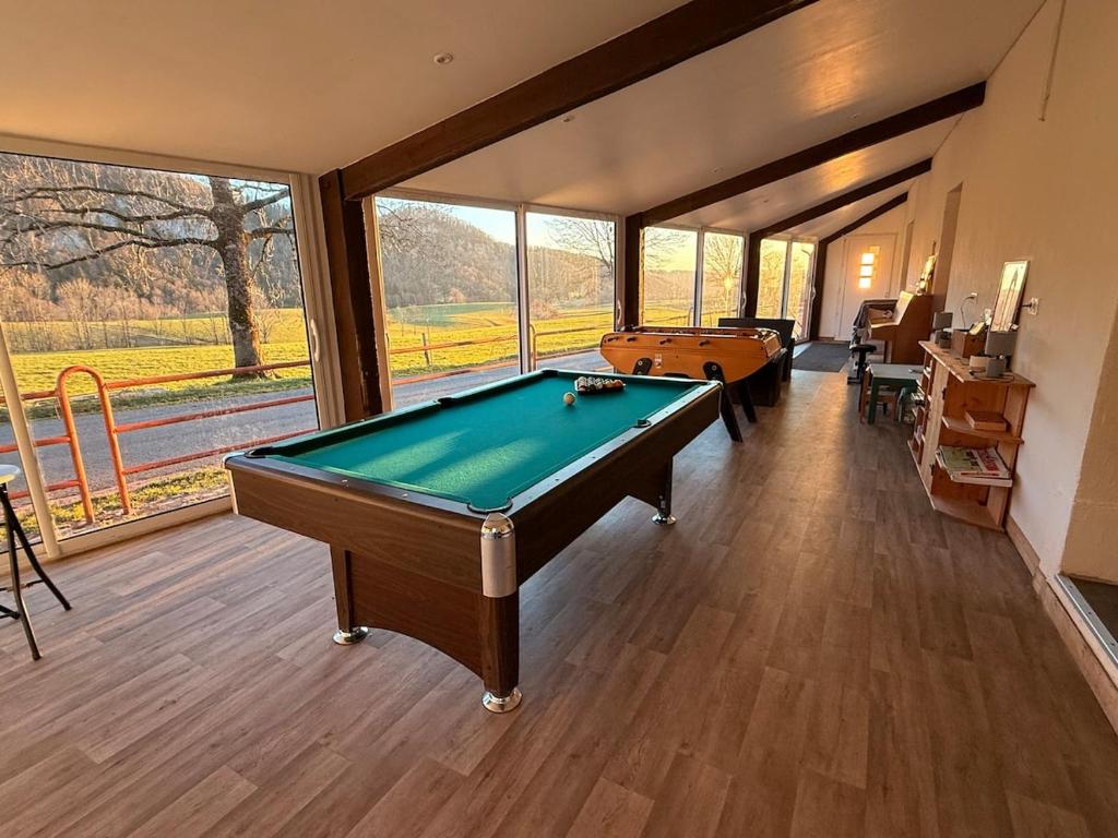 a billiard room with a pool table and windows at La colonie in La Perrena