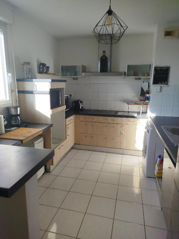 a large kitchen with white tile floors and appliances at Bel appartement 3 pièces climatisation in Saint-Alban